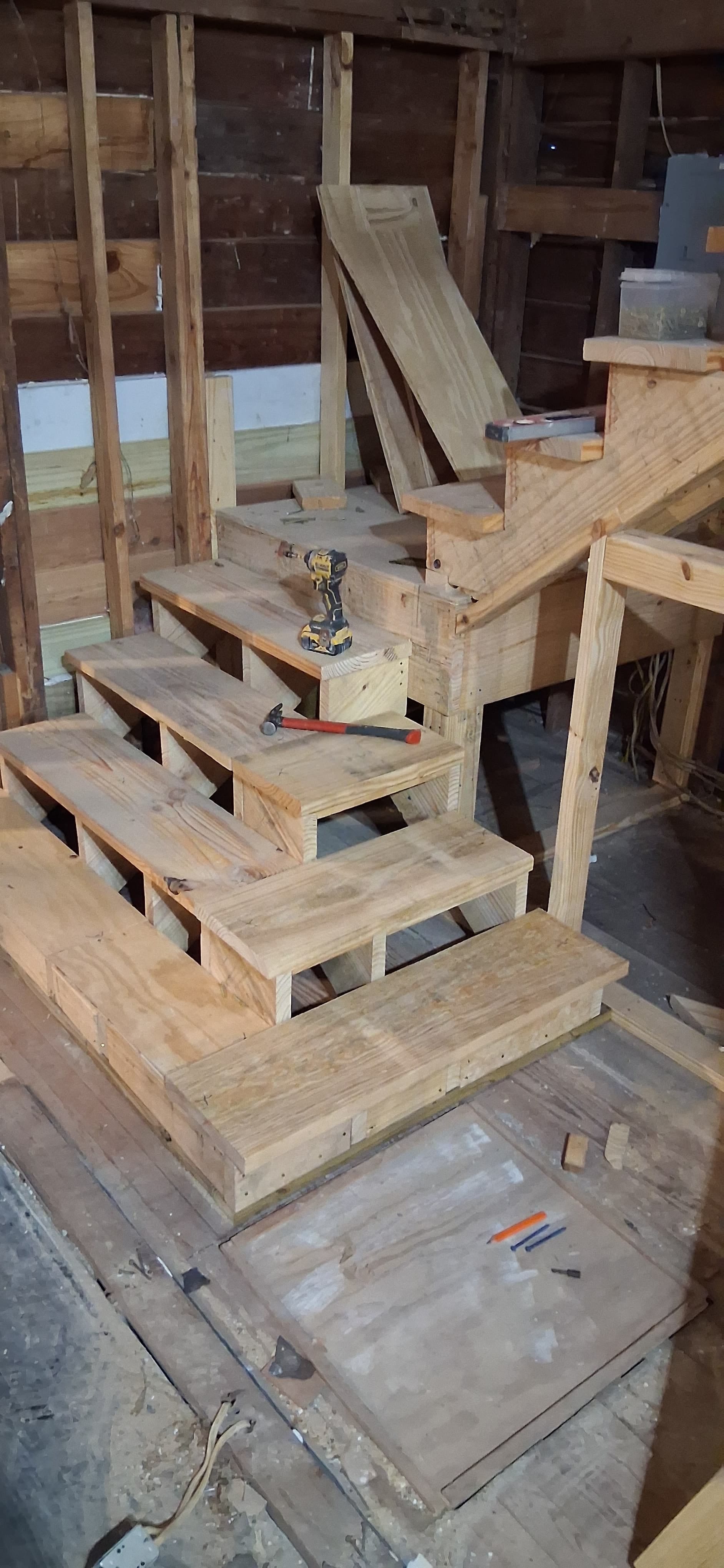 The same wood staircase after treads were fitted to the stringers beside a framed landing, before finish materials and railings.