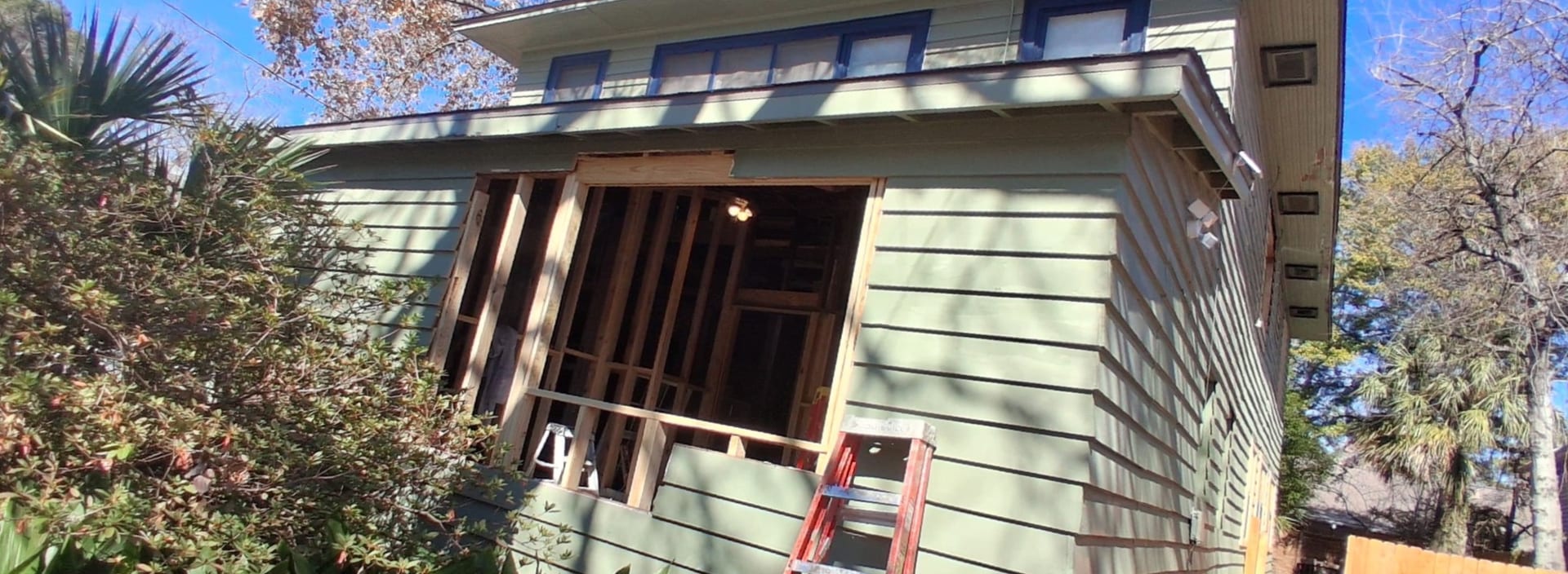 Front wall of the same house opened to expose framing during window installation.