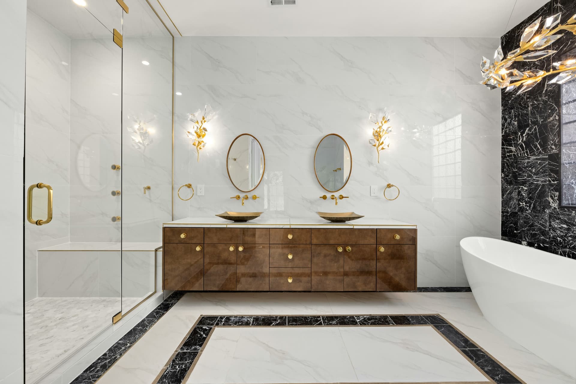 Primary bathroom remodel with green vanity, marble shower, brass fixtures, and twin mirrors.