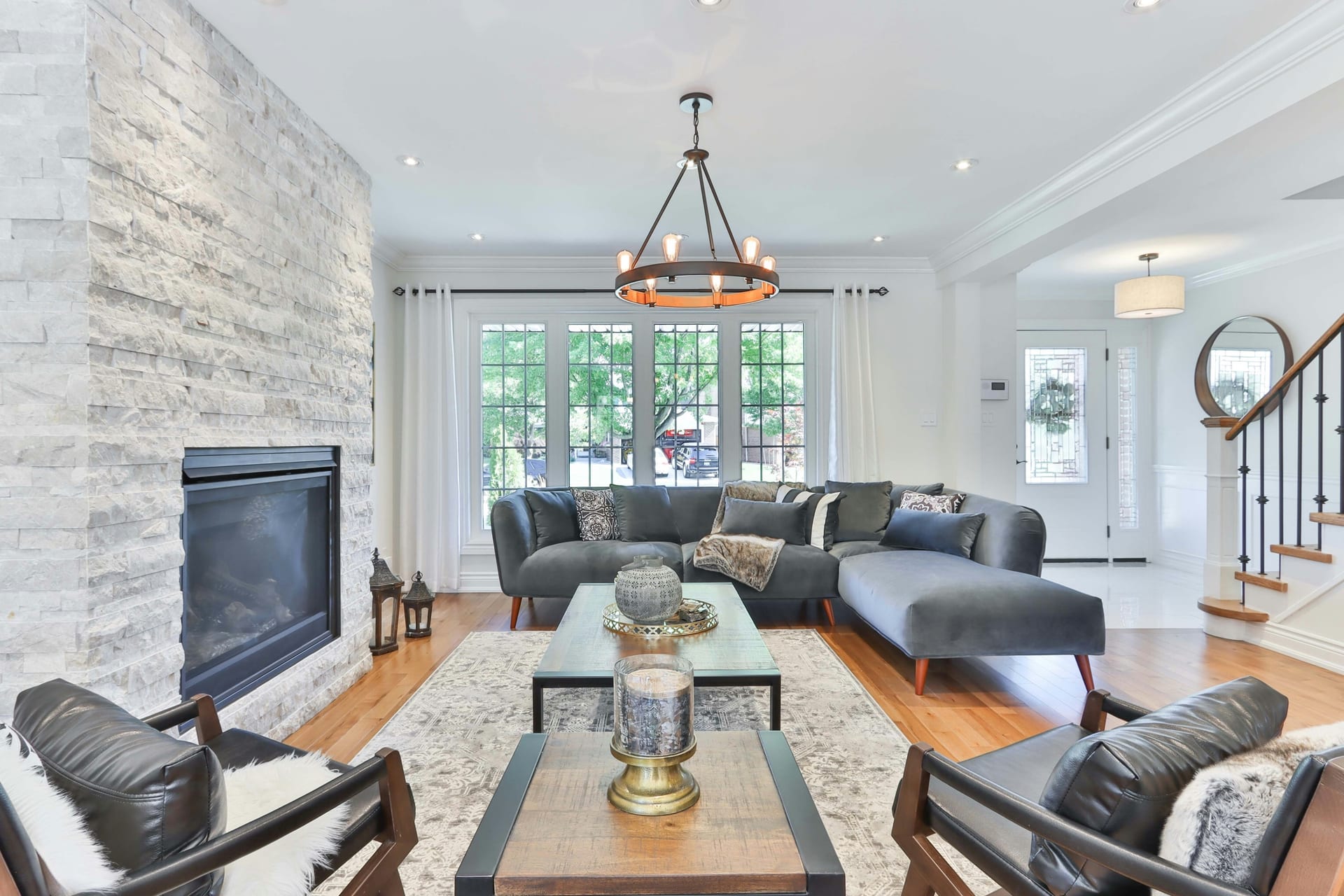 Bright living room with a stone fireplace, hardwood floors, and large windows.