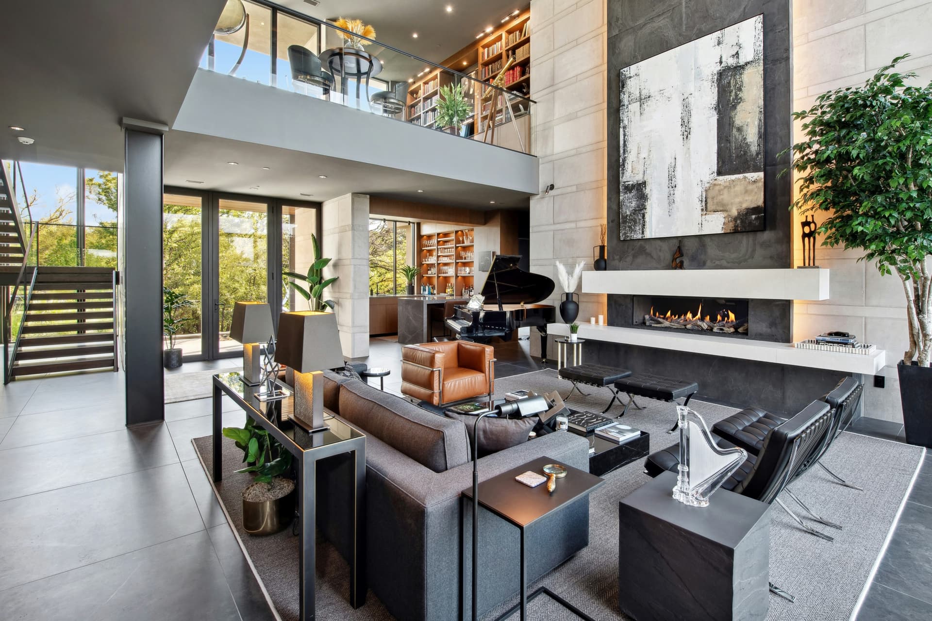 Open-plan luxury living remodel with fireplace, piano, custom built-ins, and glass rail.