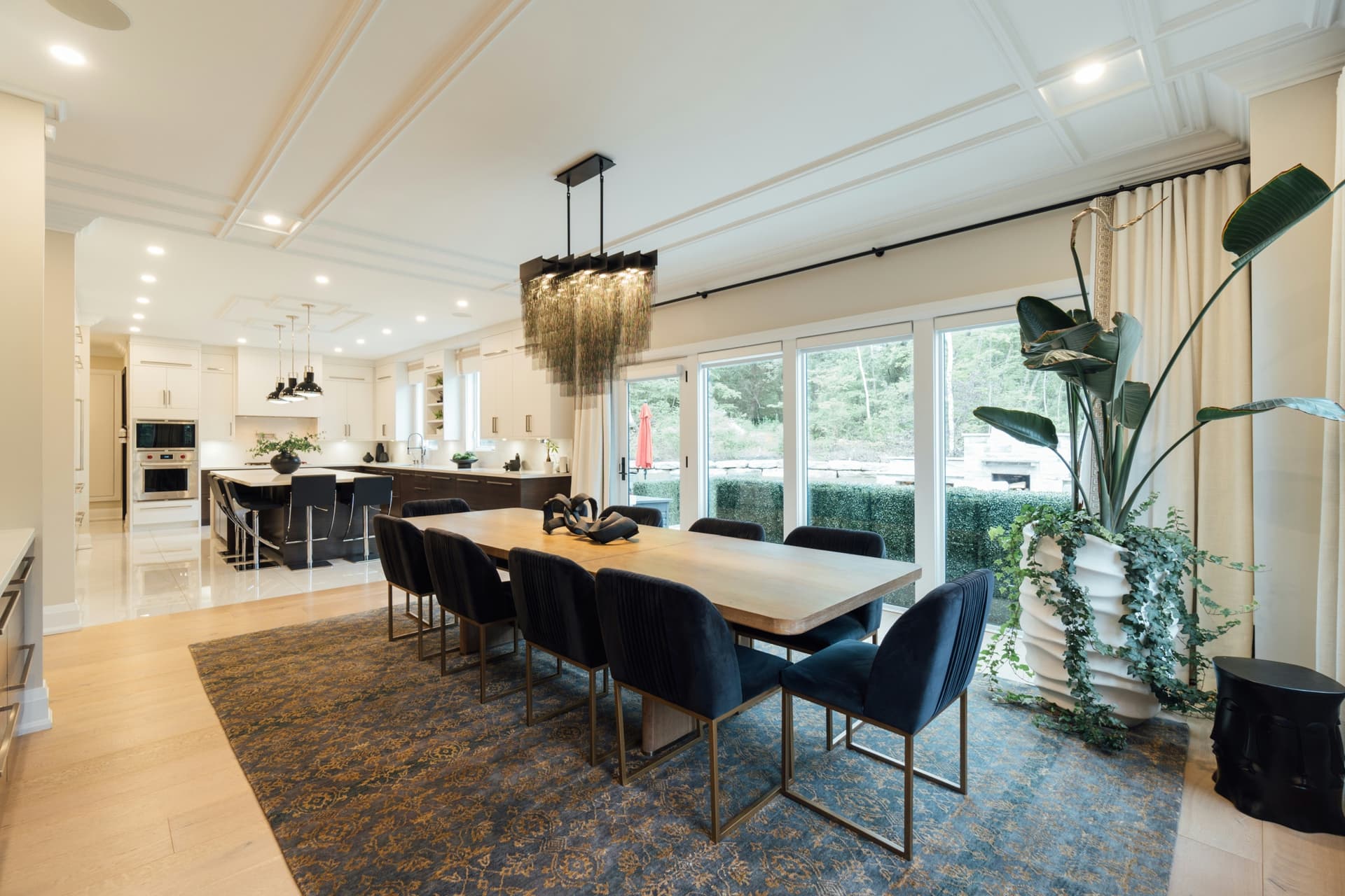 Luxury kitchen and dining remodel with coffered ceiling, large island, and tall glass doors.
