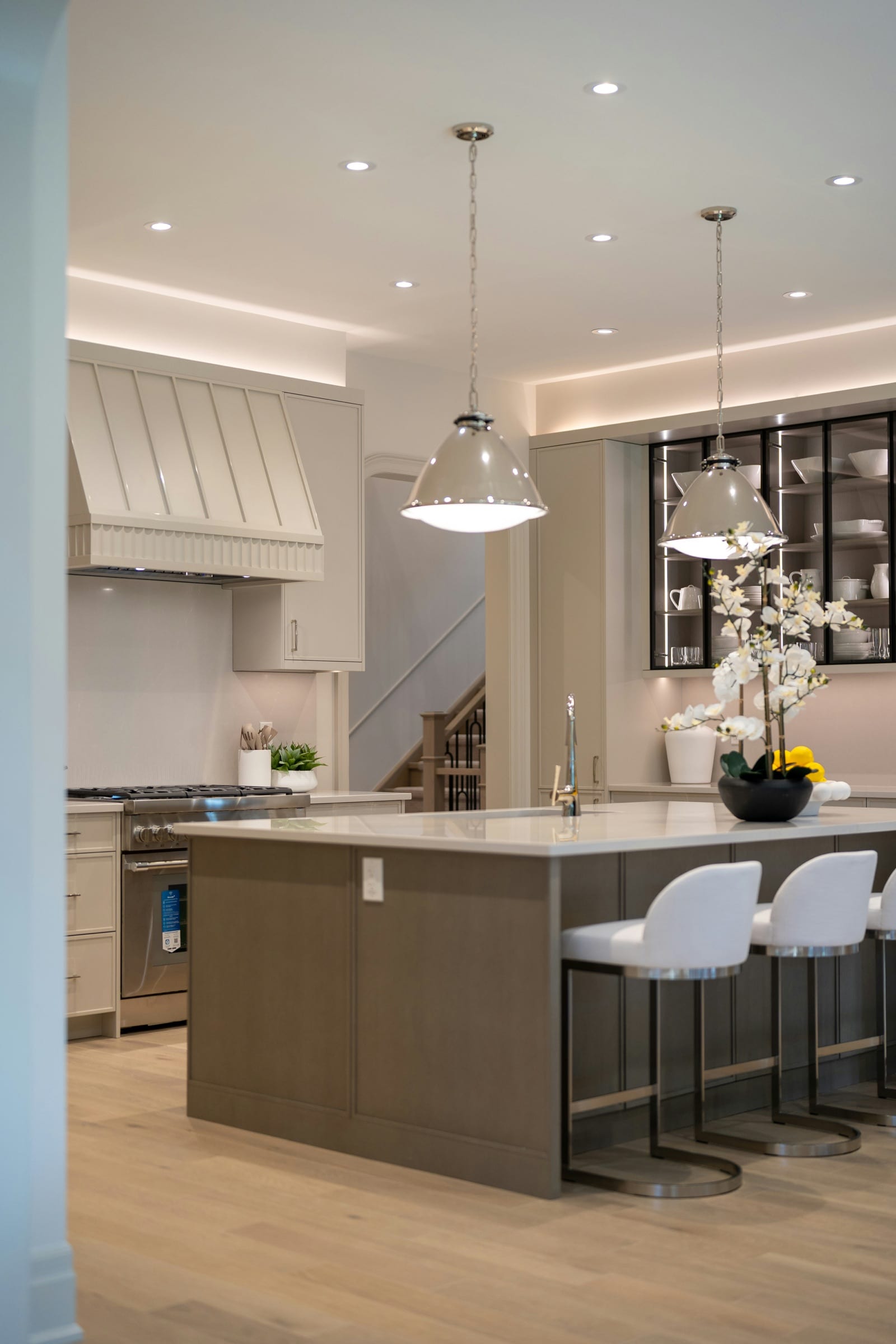Warm wood kitchen cabinetry with marble counters, professional range, and stone tile floor.
