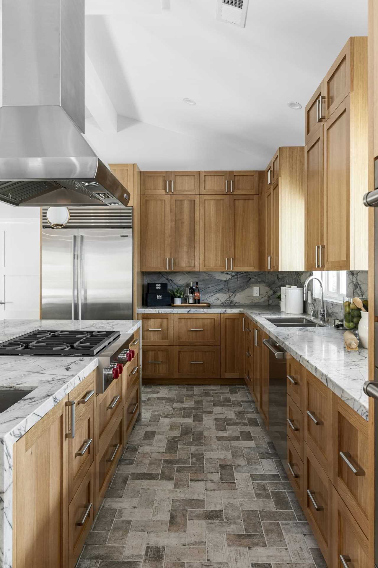 White kitchen cabinetry with brass pulls, tile backsplash, and styled counter detail.