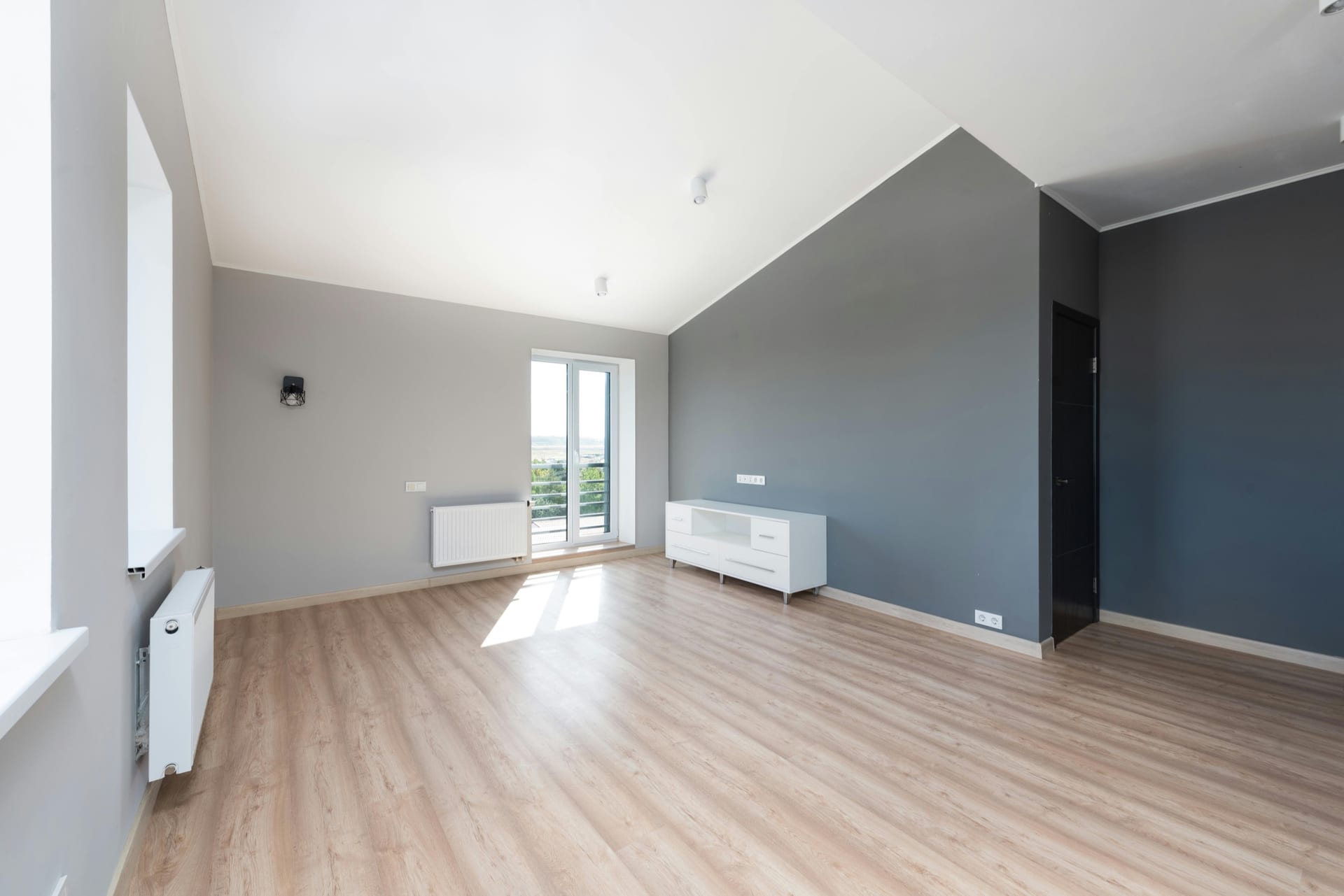 Dark interior door and frame beside gray walls and a light wood floor.